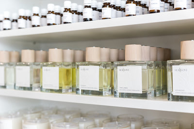 A neatly arranged shelf displaying a collection of fragrance bottles and scented candles with minimalist packaging.