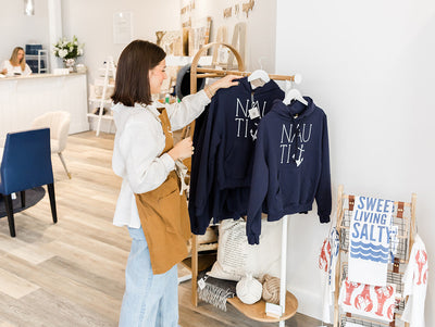 A woman browsing through clothes on a rack in a bright and modern boutique.